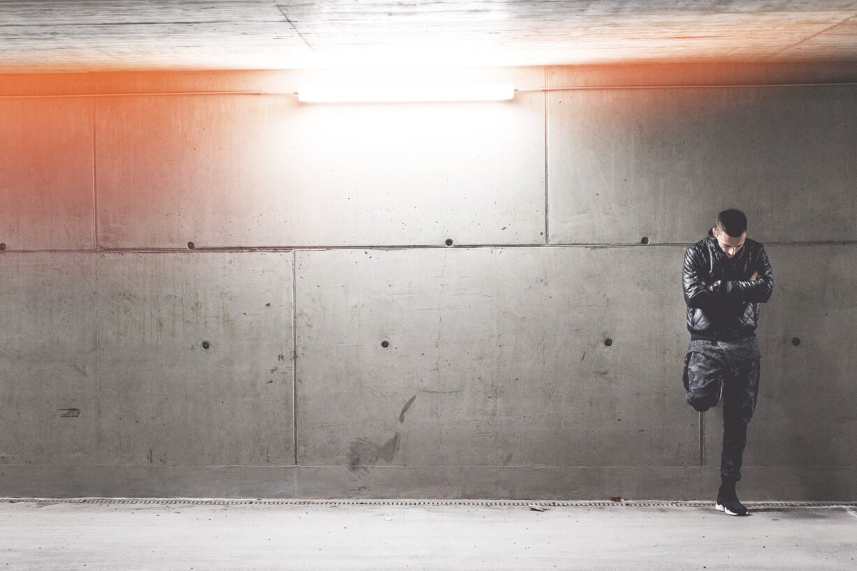 Man standing against a concrete wall.